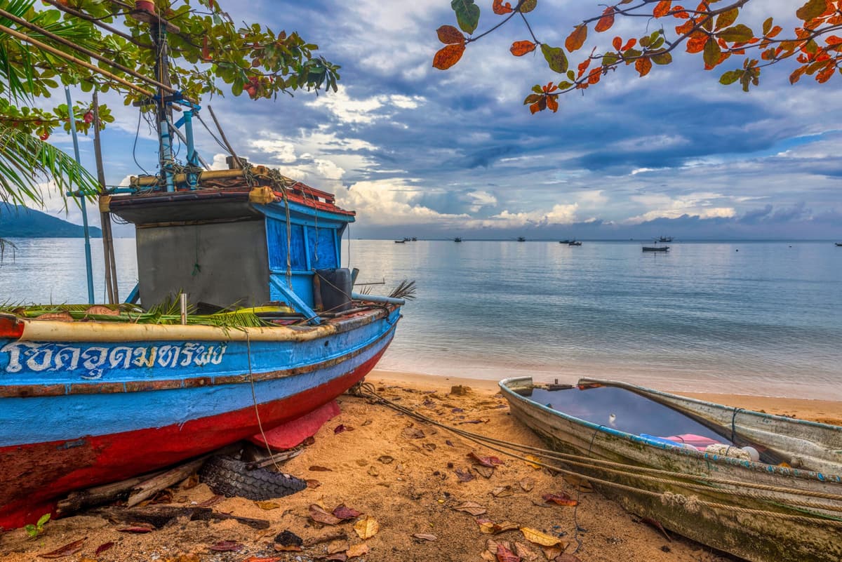 Un bateau de pêche peint, tiré sur le sable au bord de la mer d’Andaman